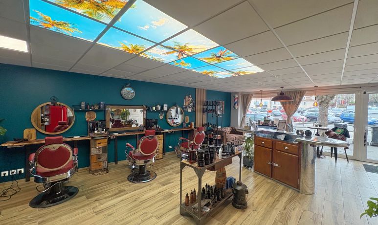 Le salon BARBER 66 : fauteuils de barbier rétro rouges, murs bleu canard et plafond ciel