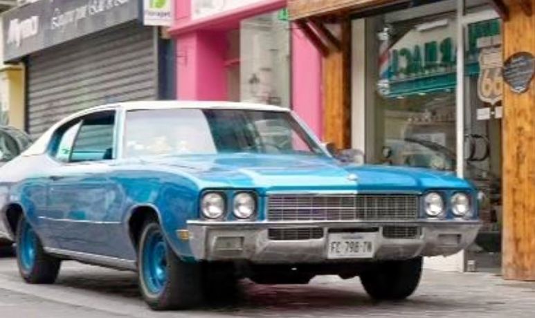 Voiture américaine vintage bleue devant le salon
